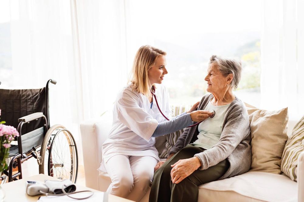 A nurse performs a medical check-up on an elderly patient during a home visit.