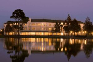 A building illuminated at night with its reflection on a calm body of water.