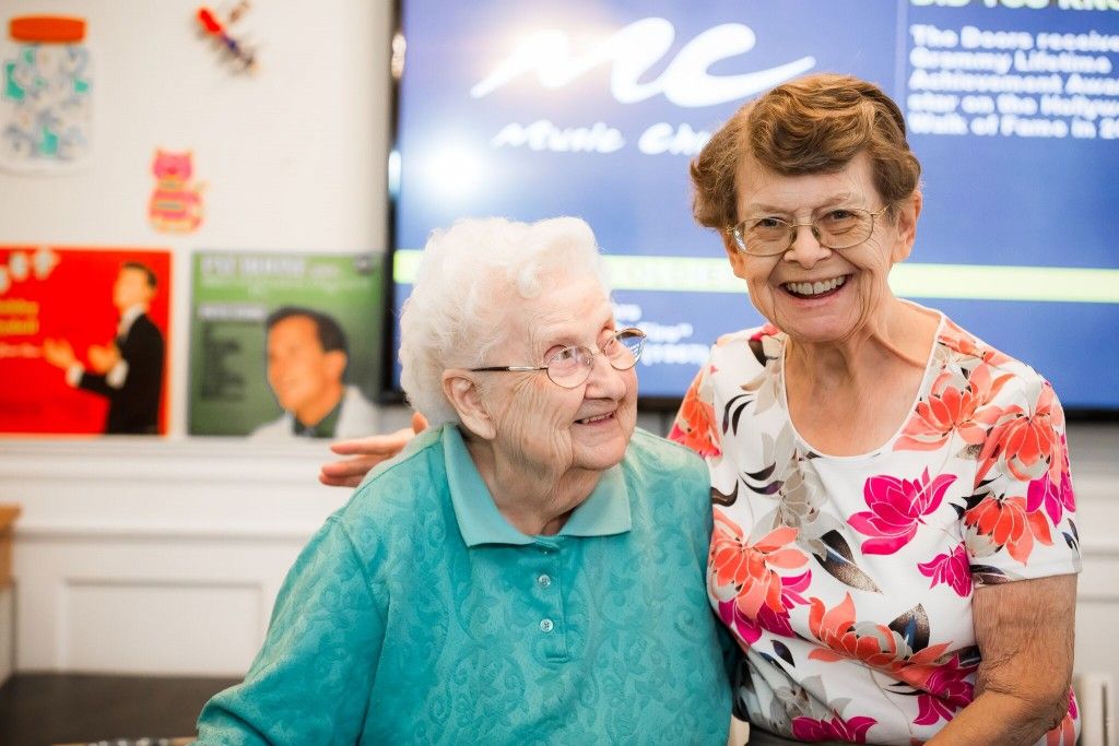 Two elderly women smiling and enjoying their time together indoors.