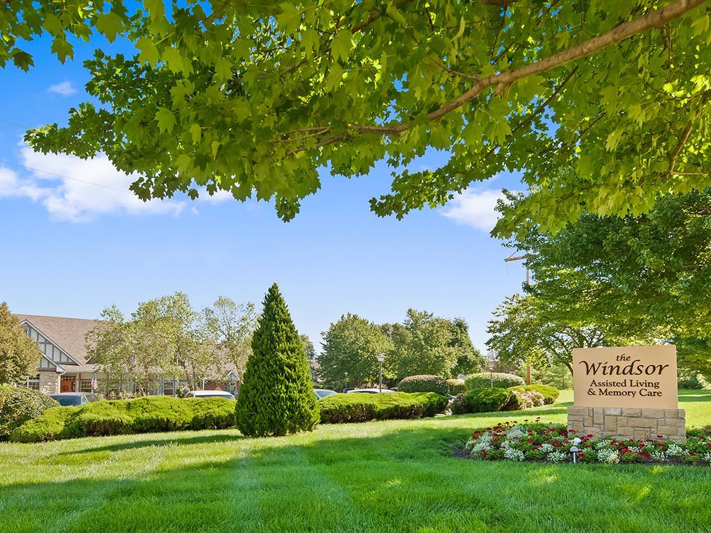 A landscaped park area with lush greenery and a sign under a clear blue sky.