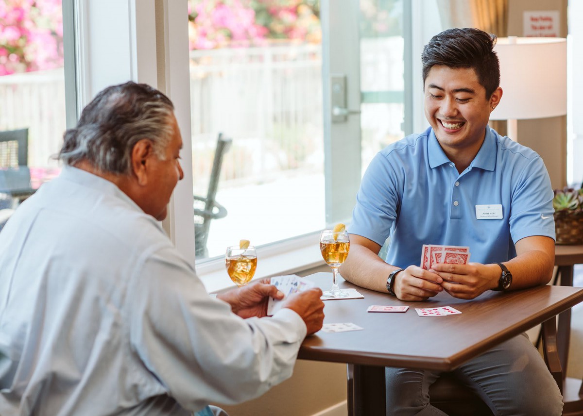 Two people enjoying a card game at a table indoors.