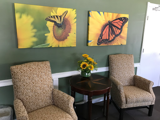 A cozy seating area featuring butterfly artwork and a vase of sunflowers.