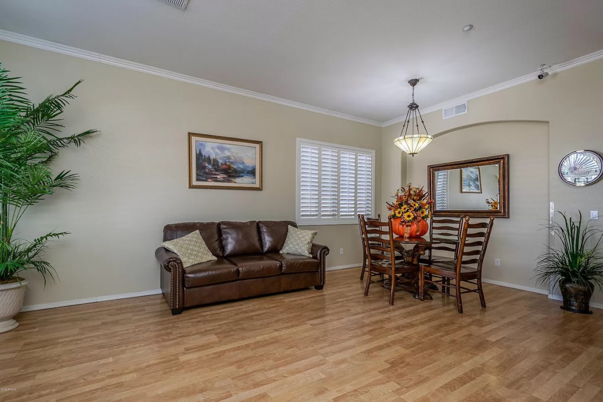 A cozy living and dining area with a leather couch, dining table, chandelier, and elegant decor.