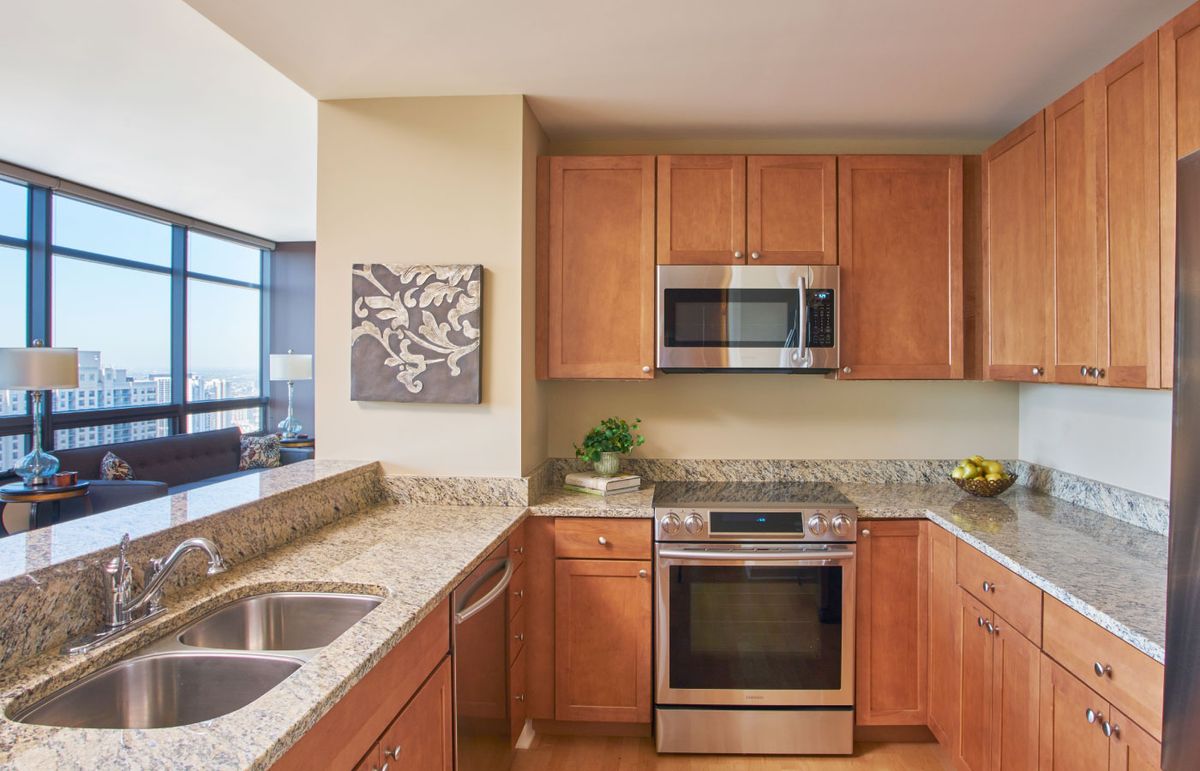 A modern kitchen with wooden cabinets, granite countertops, and stainless steel appliances.