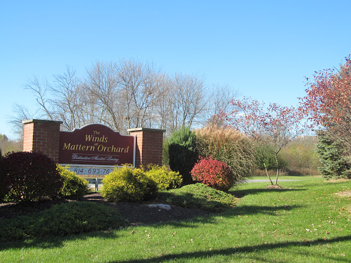 A welcoming sign surrounded by lush greenery and a clear blue sky.