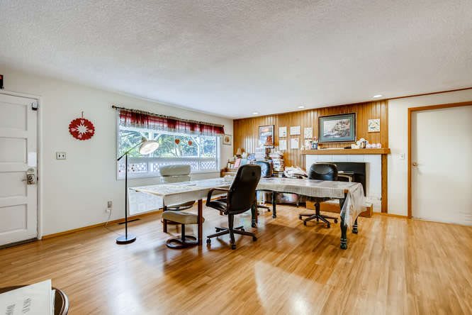 A spacious office with multiple workstations, featuring wooden floors and large windows.
