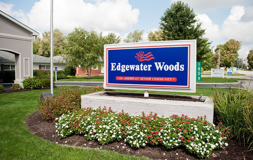 A sign for Edgewater Woods nursing home surrounded by well-maintained landscaping and flowers.
