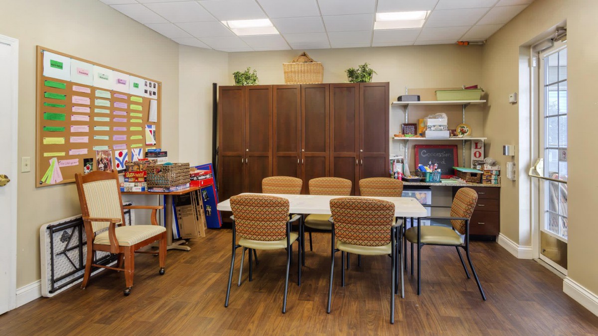 A well-organized classroom with a table, chairs, and shelves filled with educational materials.