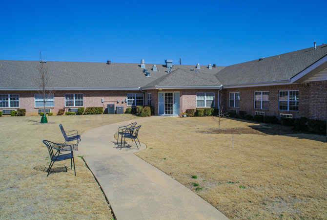 A residential building with a central courtyard featuring a pathway and seating area on a clear day.