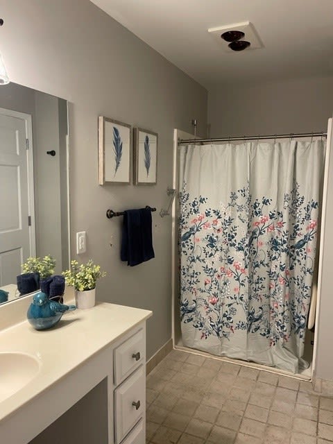 A neatly organized bathroom with floral shower curtain and decor.