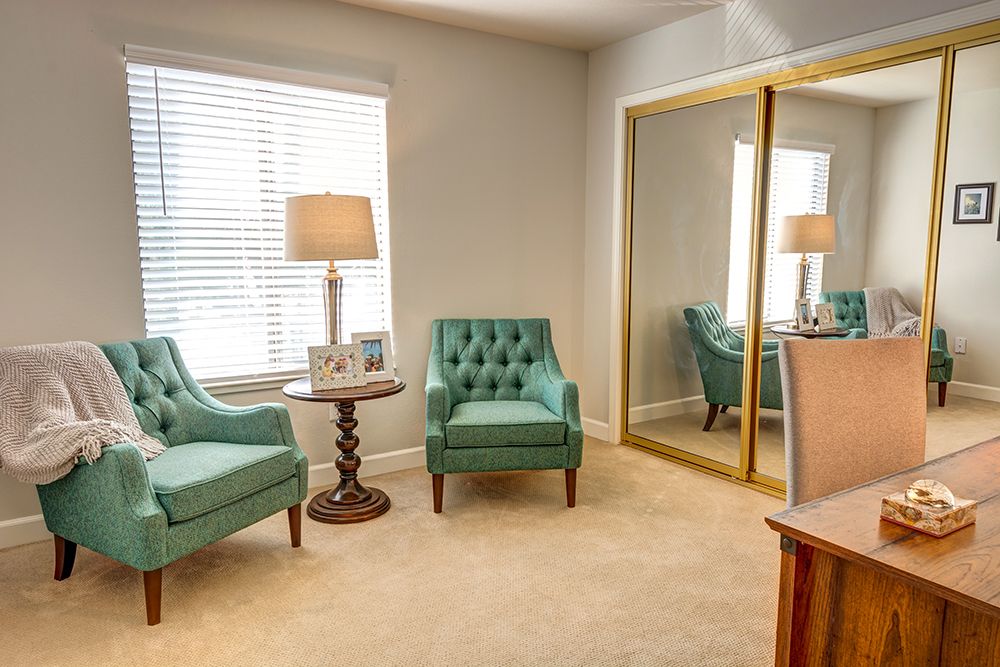 A cozy living room with teal armchairs and a large mirrored closet.