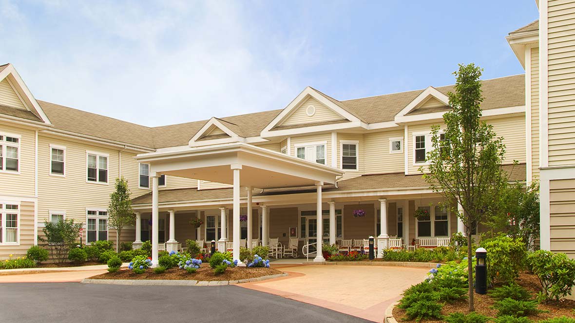 A large residential building with a porch and landscaped front yard.