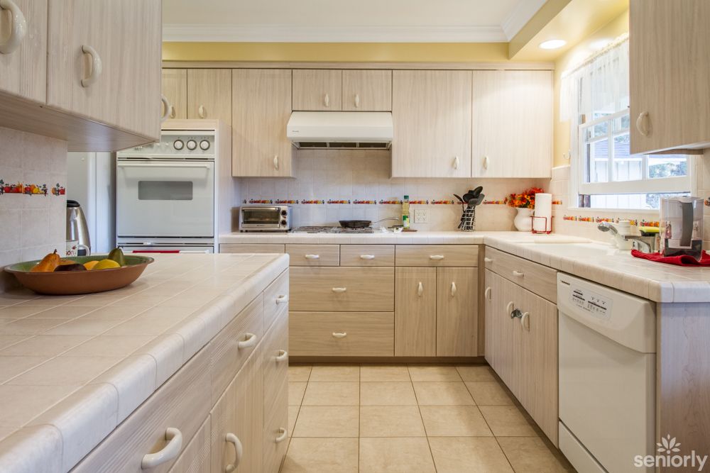 A modern kitchen with light wood cabinets and various appliances.