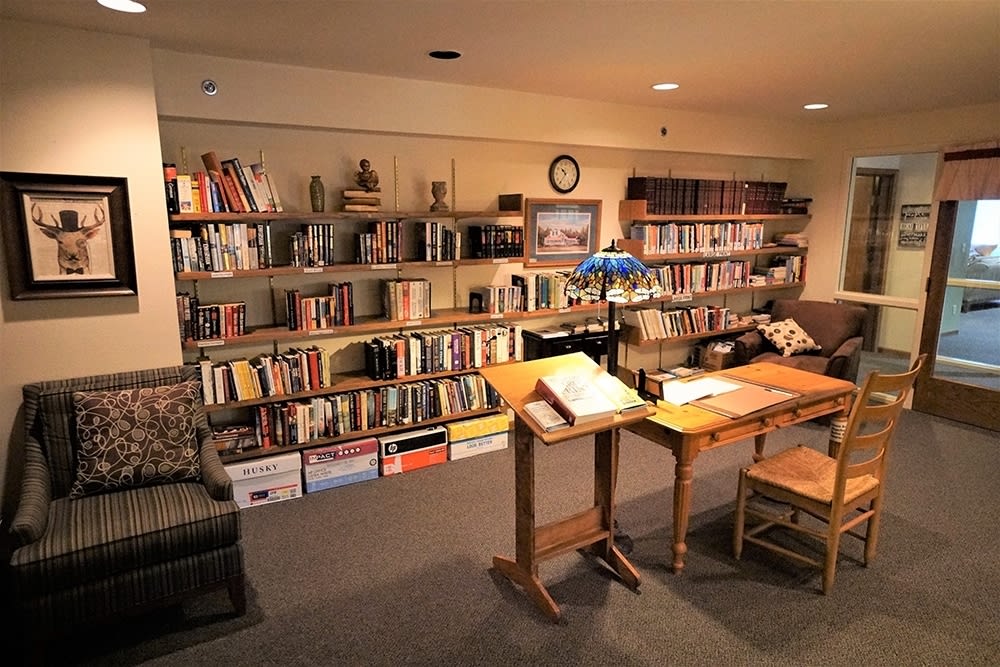 A cozy library corner with bookshelves, tables, and comfortable seating.