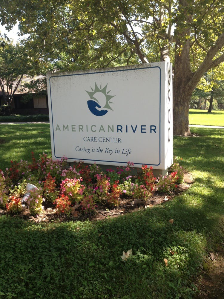 A sign for American River College surrounded by greenery and plants.