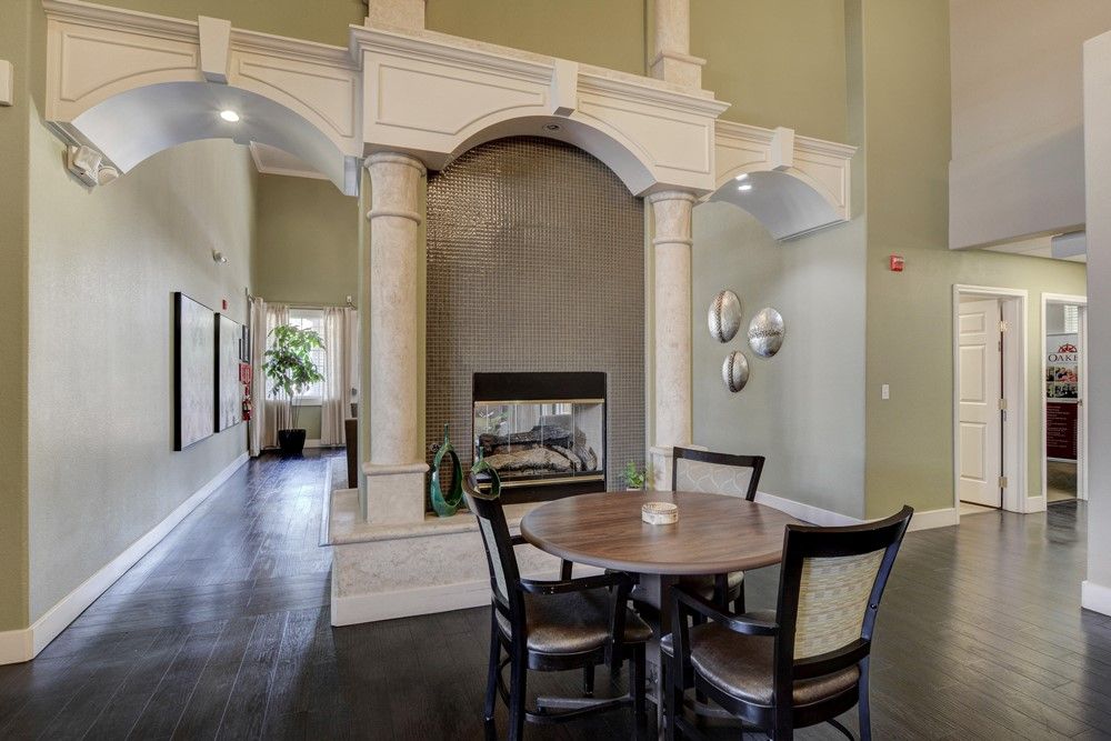 A modern dining room with a round table and chairs, featuring a fireplace framed by decorative columns.