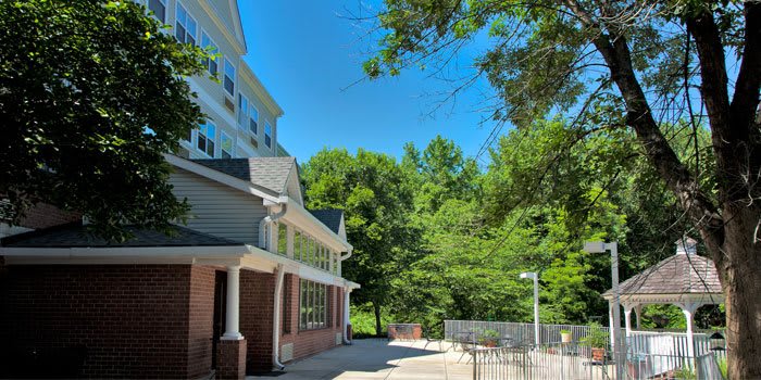 A sunny day with a building and lush green trees under a clear blue sky.