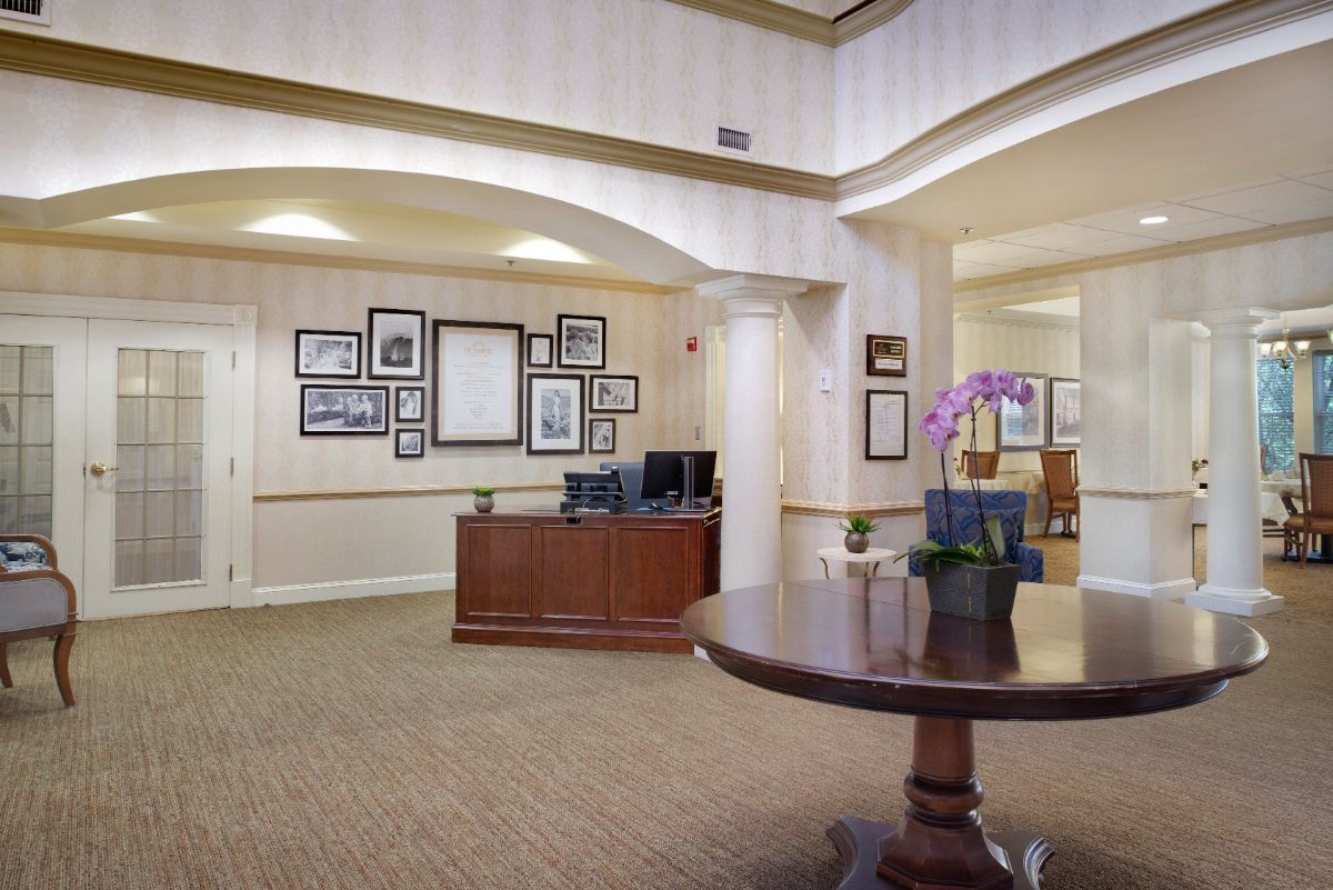 A welcoming reception area featuring a wooden desk, wall art, and a table with a flower vase.