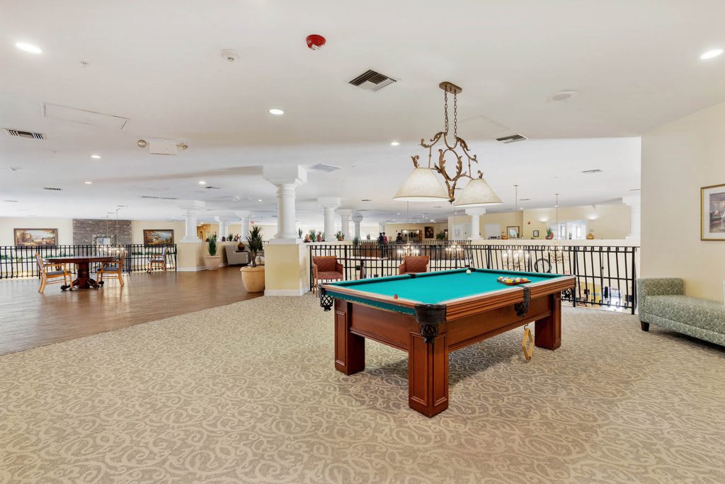 A spacious game room featuring a pool table under a decorative chandelier.
