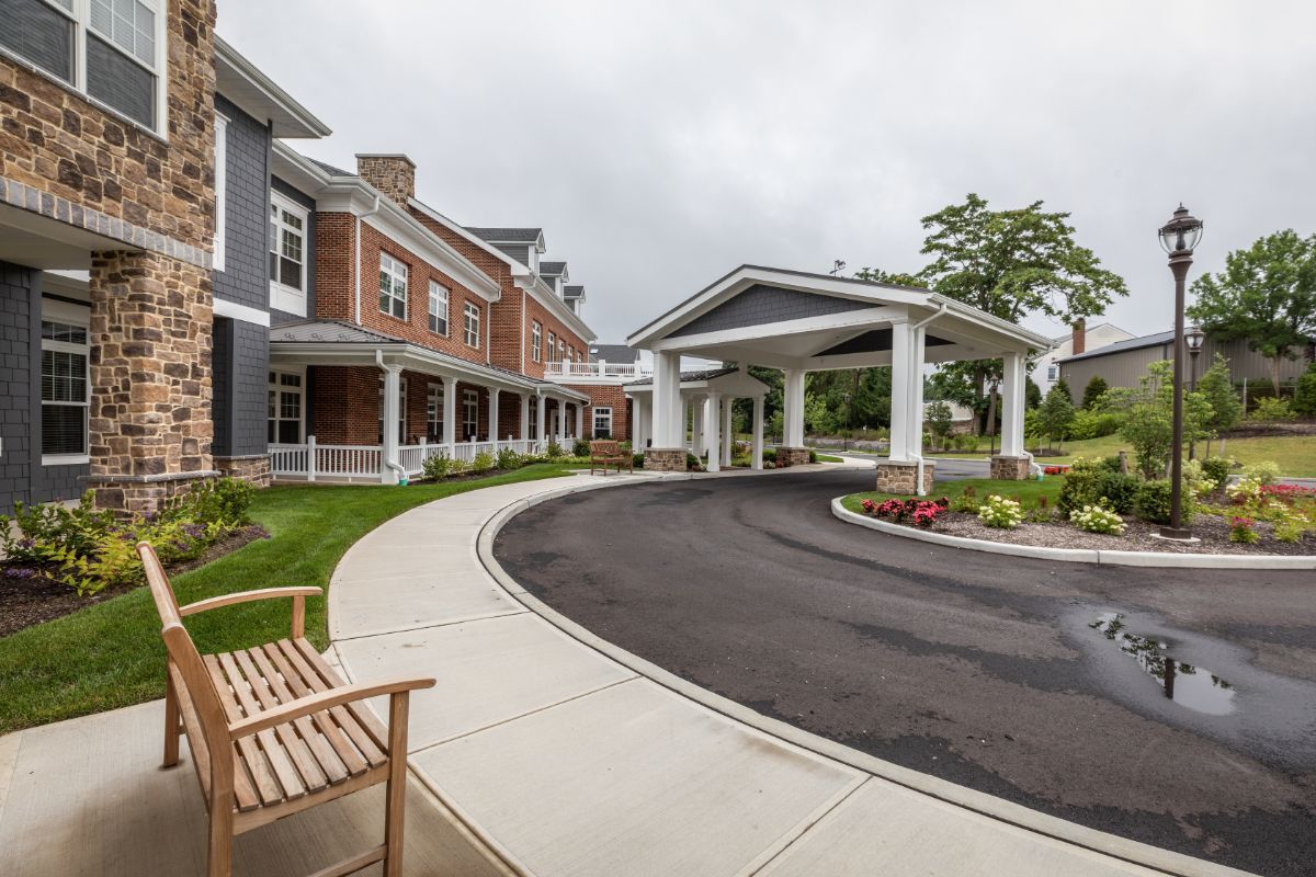 A modern building with a covered entrance and landscaped driveway on a cloudy day.