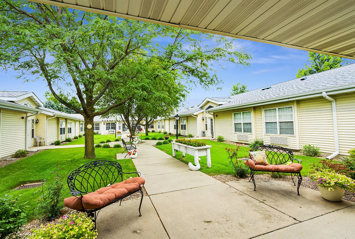 A picturesque courtyard with benches, trees, and surrounding buildings.