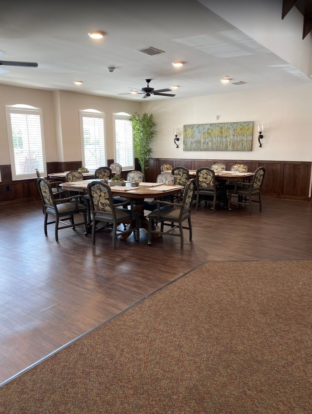 A spacious dining area with multiple tables and chairs, featuring ample natural light from the windows.
