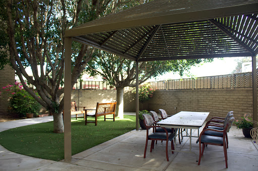 A serene garden setting featuring a gazebo, outdoor table, and comfortable seating.