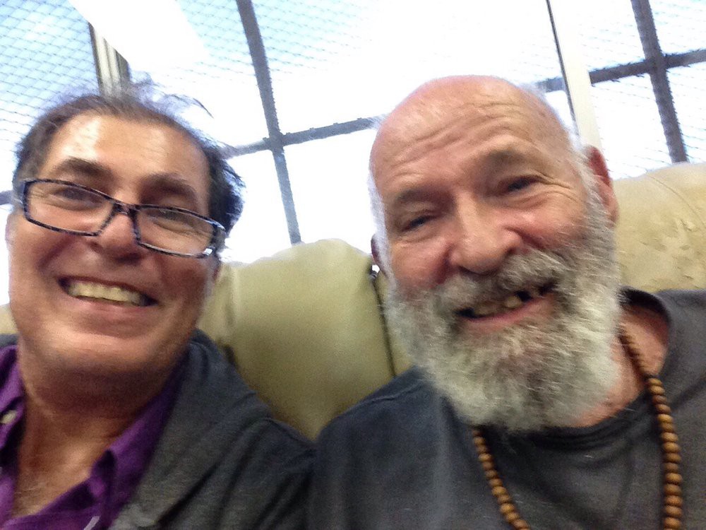 Two smiling individuals taking a selfie indoors.