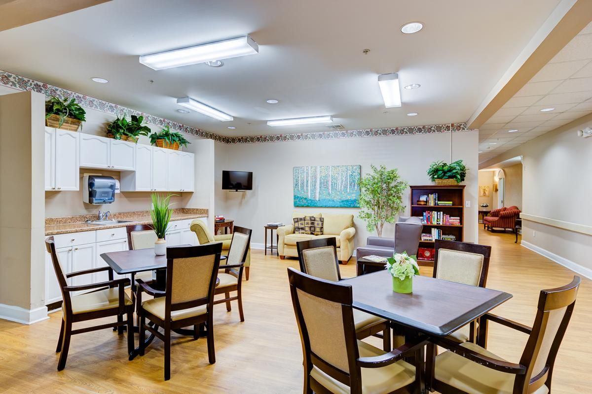 A cozy dining area with neatly arranged tables and chairs, decorated with plants and warm lighting.