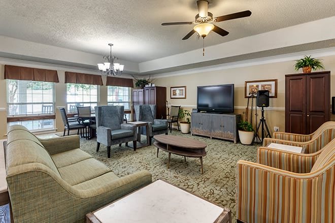 A cozy living room with ample seating, a large television, and a ceiling fan.