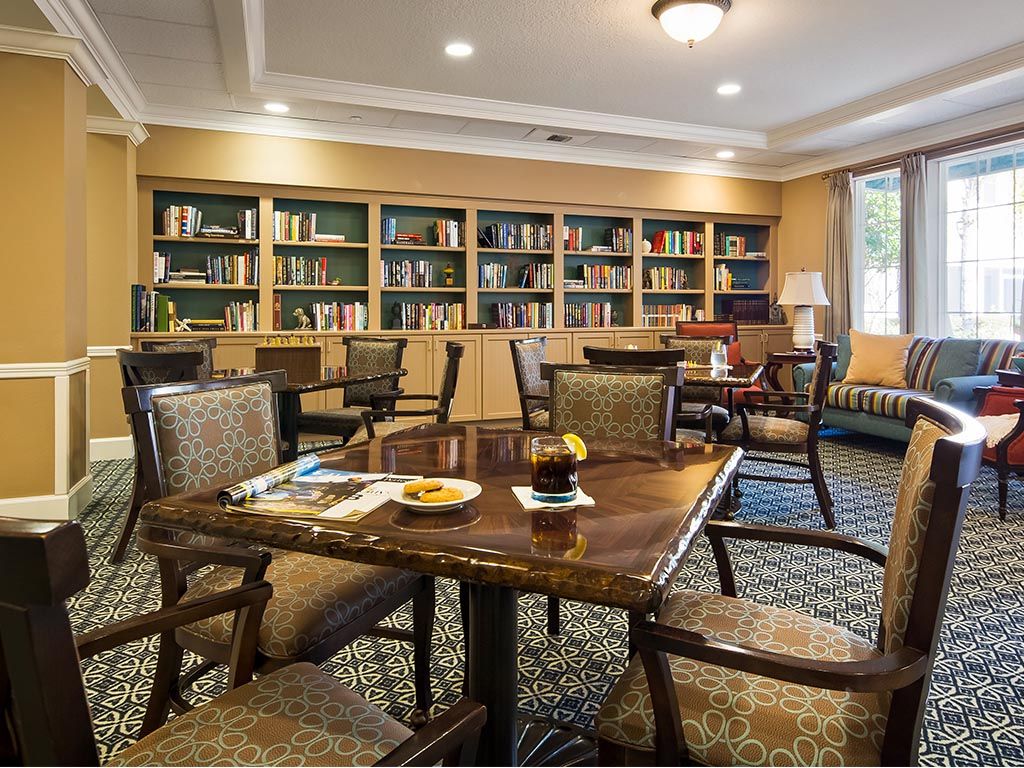 A cozy library reading room with bookshelves, tables, and chairs.
