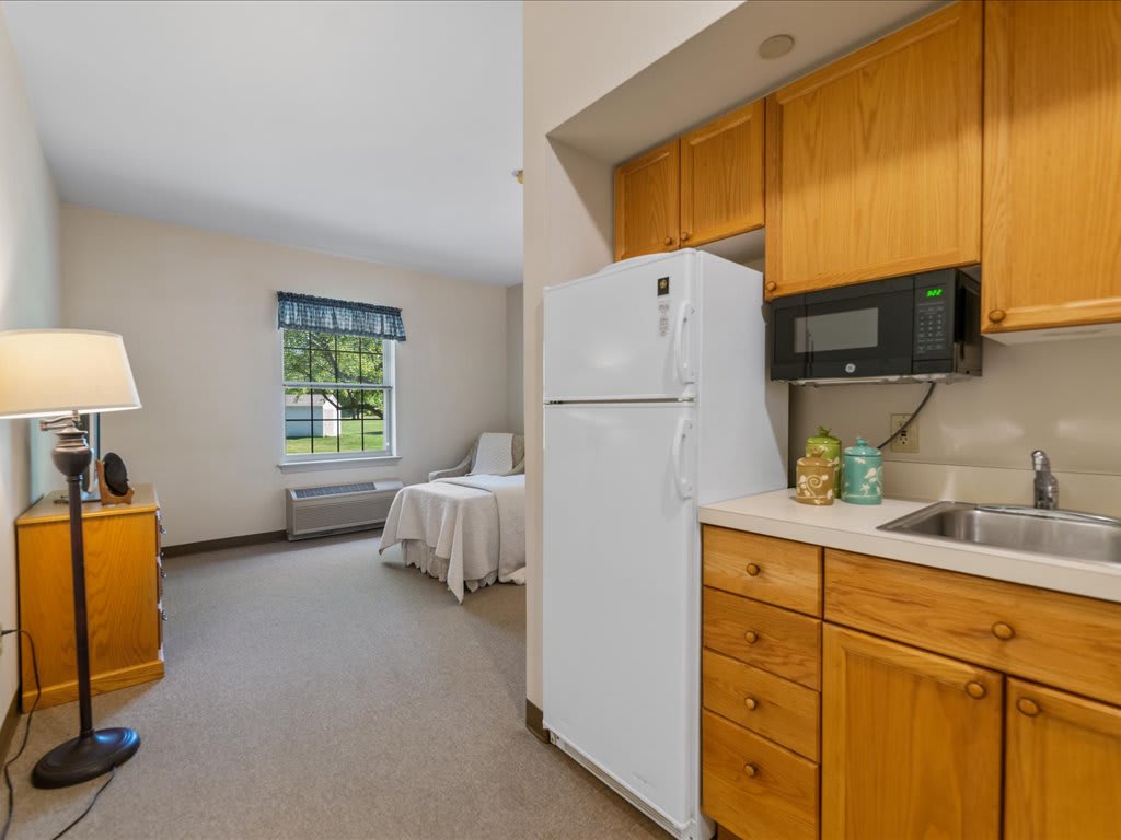 A cozy apartment kitchen with wooden cabinets, a white fridge, and a microwave.