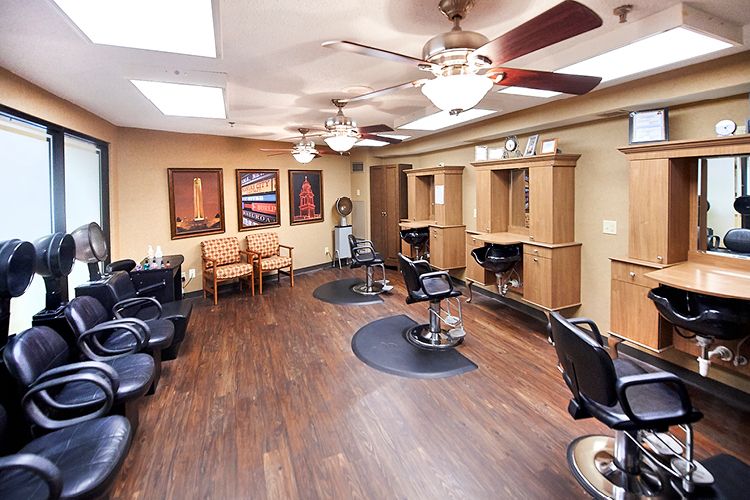 A cozy hair salon interior with chairs and mirrors arranged on wood flooring.