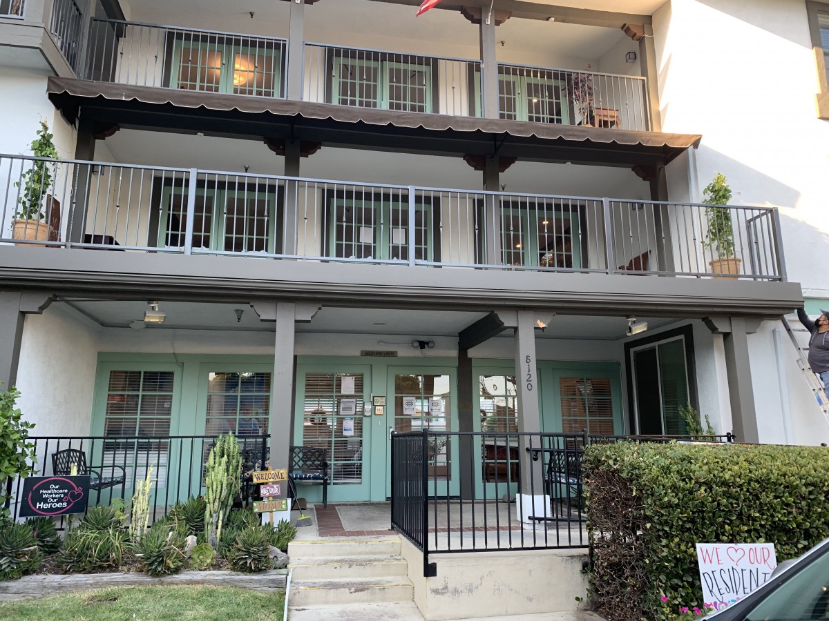 A multi-story residential building with balconies and a front porch.