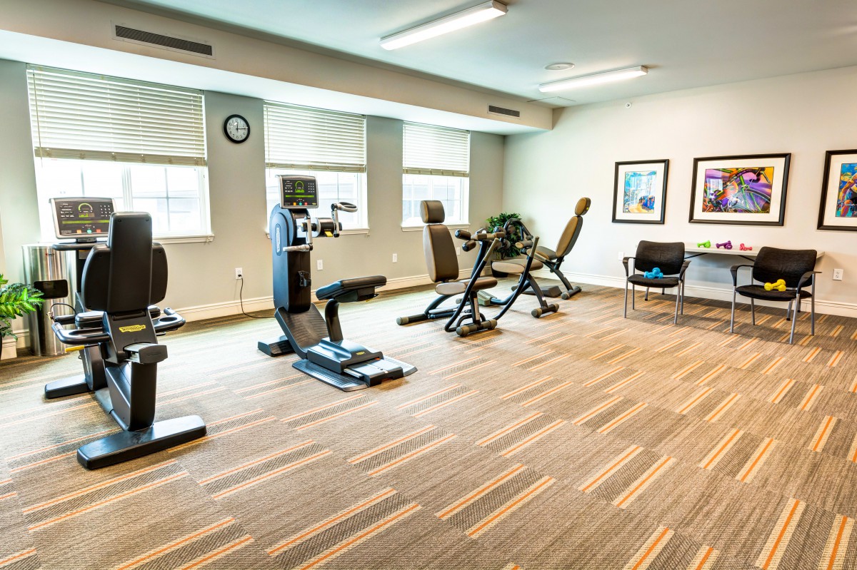 A modern gym with exercise equipment, including treadmills and a stationary bike, in a well-lit fitness room.
