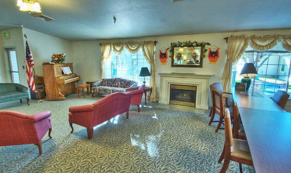 A cozy living room with a piano, red couch, and fireplace.