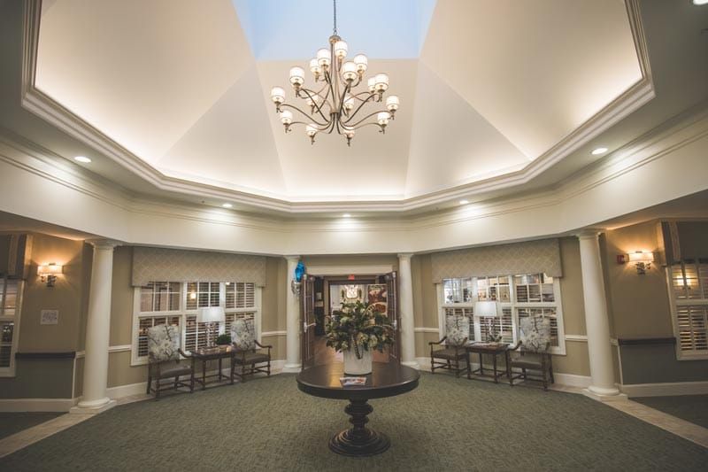 Elegant lobby interior with a central chandelier and large windows.