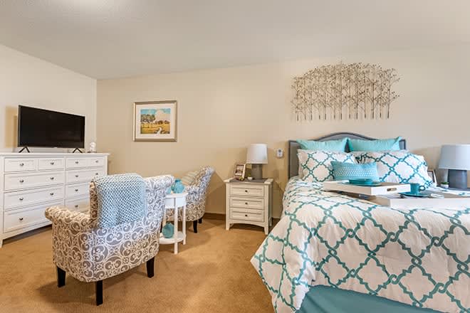 A stylishly decorated bedroom with patterned bedding and comfortable seating.