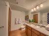 A modern bathroom with a large mirror, dual sinks, and warm lighting.