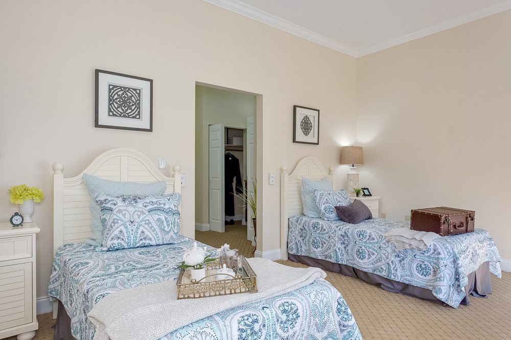 A cozy bedroom with twin beds featuring patterned bedding and elegant wall art.
