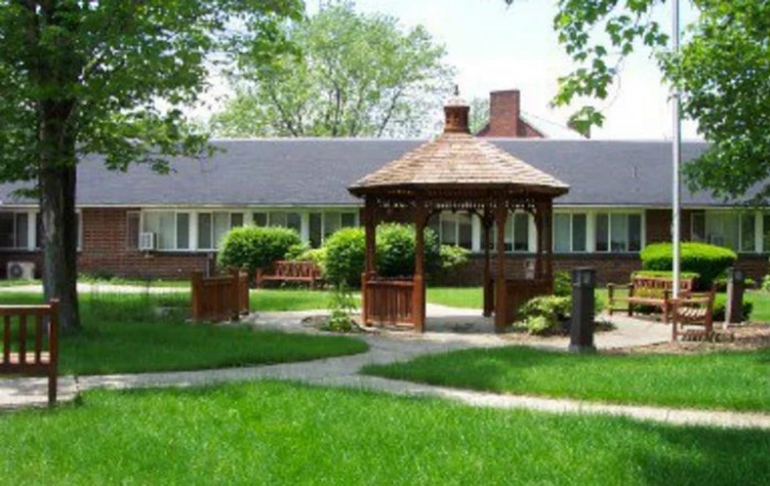 A charming gazebo in a lush garden with a house in the background.