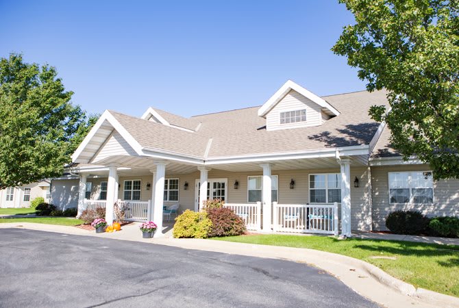 A suburban residential building with a front porch and landscaped garden.