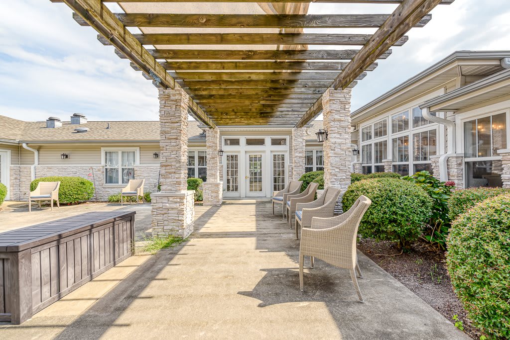 A charming outdoor patio area featuring a pergola and stone columns with comfortable seating.