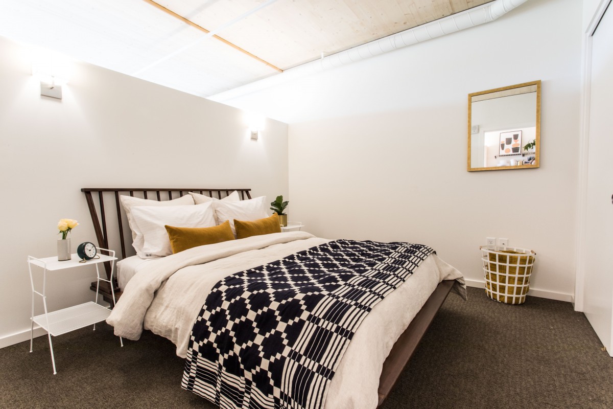 A modern and cozy bedroom with minimalist design featuring a neatly made bed and stylish decor.