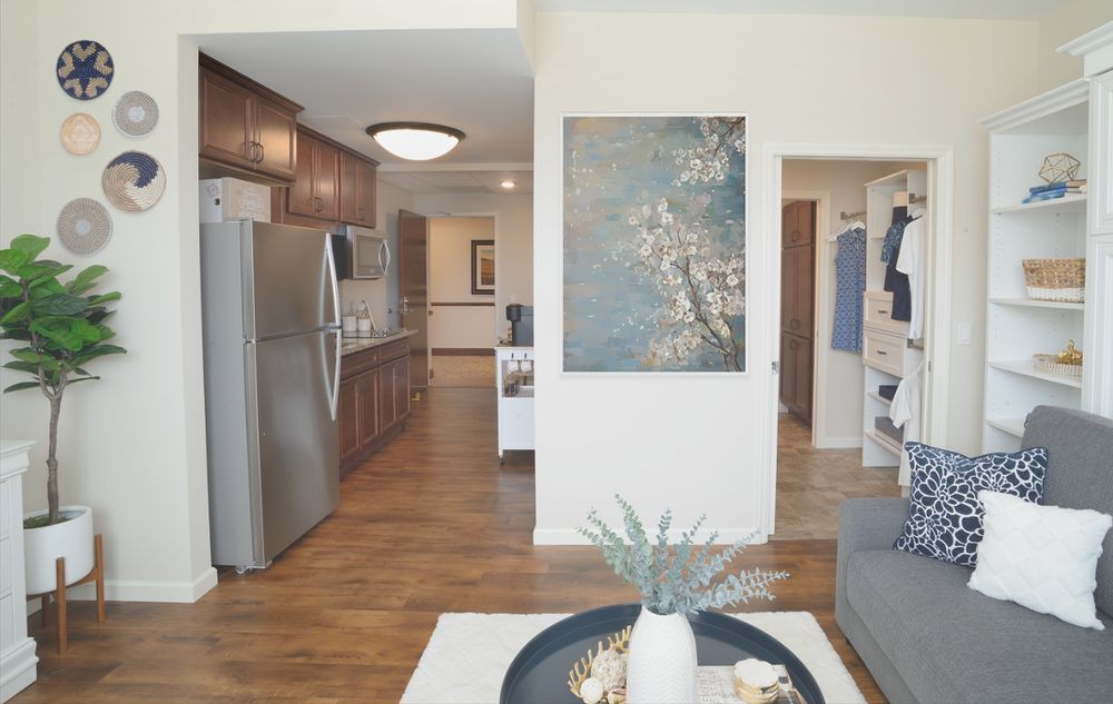 A modern open-concept interior featuring a kitchen and living area with hardwood floors and decorative artwork.