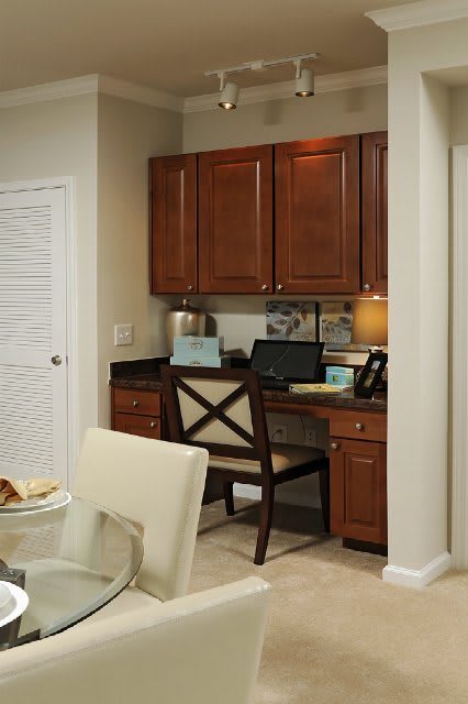 A cozy home office setup with a desk, chair, and wooden cabinets.