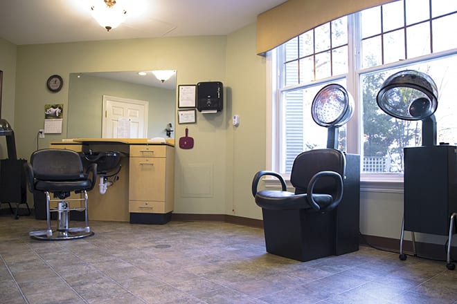 A cozy salon interior featuring a hair dryer and seating area by the window.