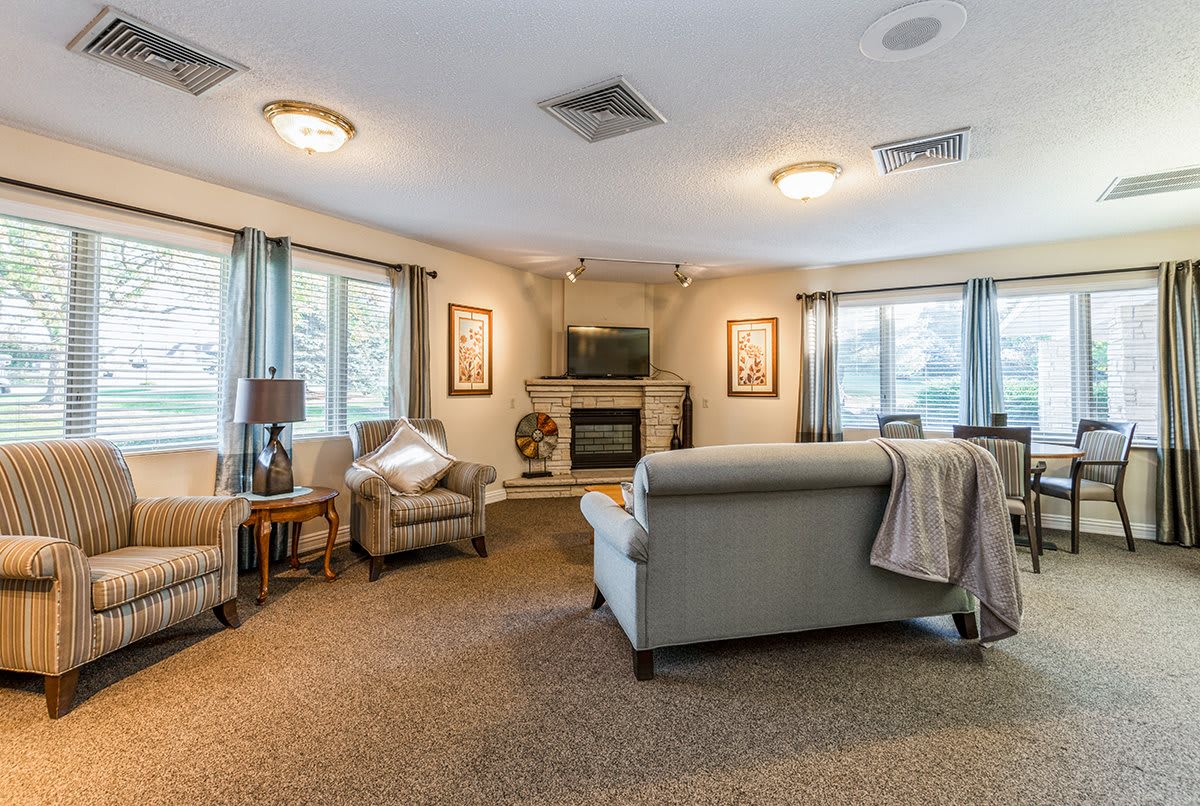A cozy living room with comfortable seating, a fireplace, and large windows allowing natural light to fill the space.
