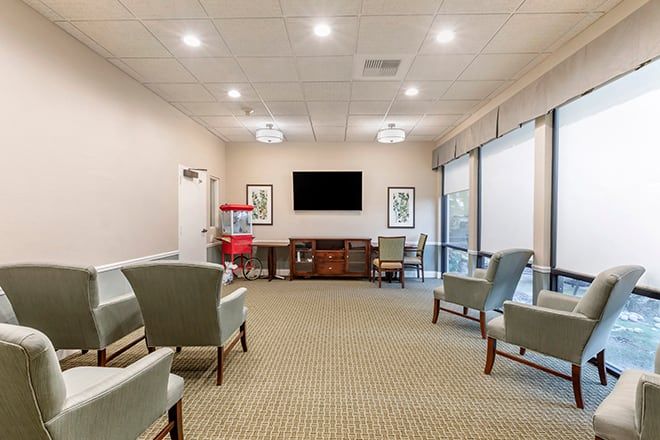 A spacious waiting room with comfortable seating and a large television.