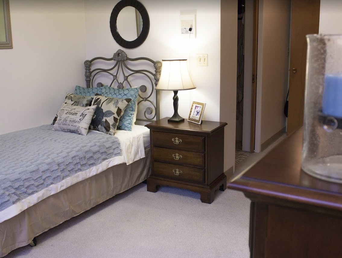 A cozy bedroom with a bed, nightstand, and lamp, featuring elegant decor.